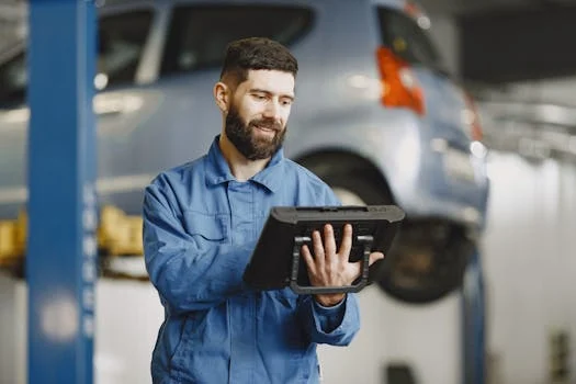 Mechanik v čistém moderním autoservisu provádějící přesnou diagnostiku vozu přes chytrý tablet